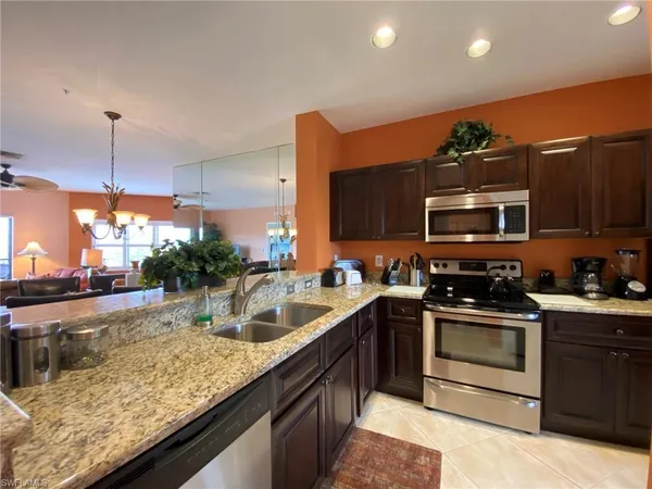 a kitchen with stainless steel appliances granite countertop a sink a stove top oven a counter space and cabinets