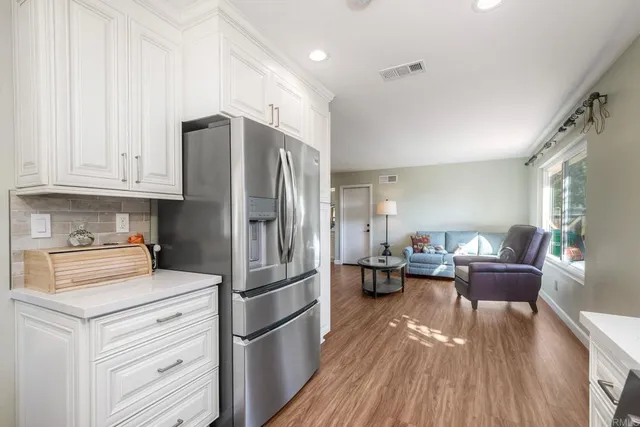 a kitchen with a refrigerator wooden floor a sink and a view of living room