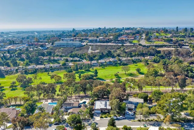 an aerial view of a house with a yard and large trees