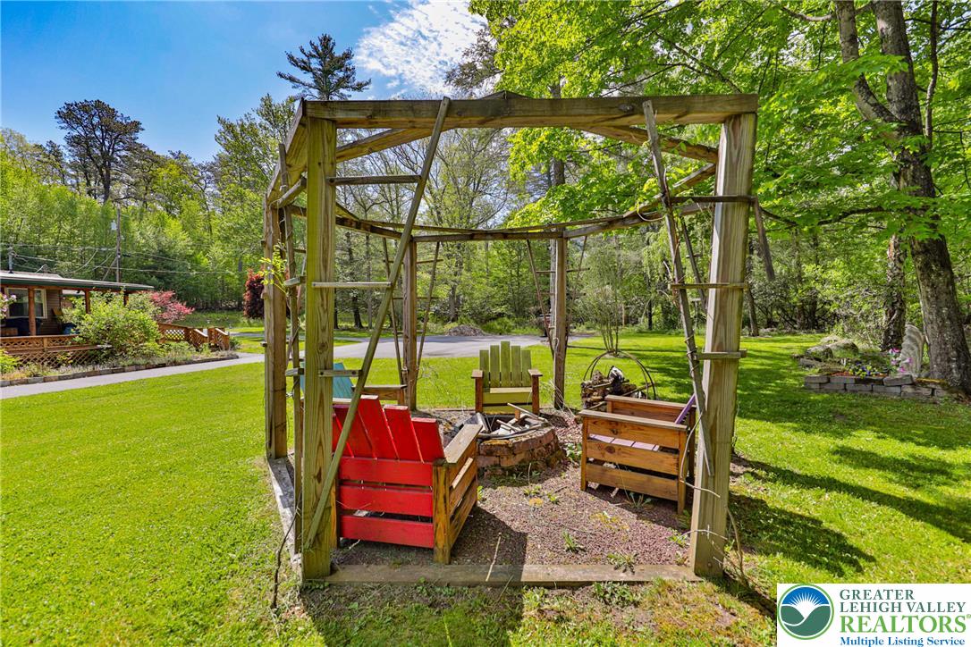 331 Cranberry Creek Road Cresco, PA 18326 - Photo 78 of 95 An inviting outdoor fire pit area with a wooden gazebo and chairs, set amidst lush green landscaping.