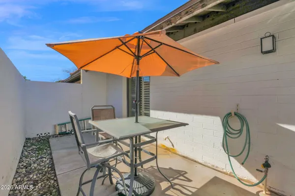 a patio with a table and chairs under an umbrella