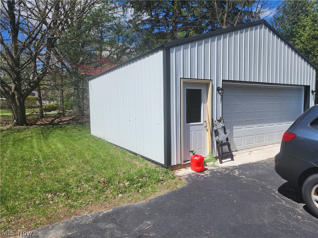 3187 Grenfall Road Barberton, OH 44203 - Photo 16 of 17 Metal-sided garage structure featuring a roll-up door, a separate entry door, and exterior lighting fixtures