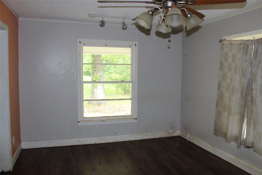 929 Forsythe Street Carthage, TX 75633 - Photo 5 of 9 Unfurnished room featuring a textured ceiling, ceiling fan, and hardwood / wood-style flooring