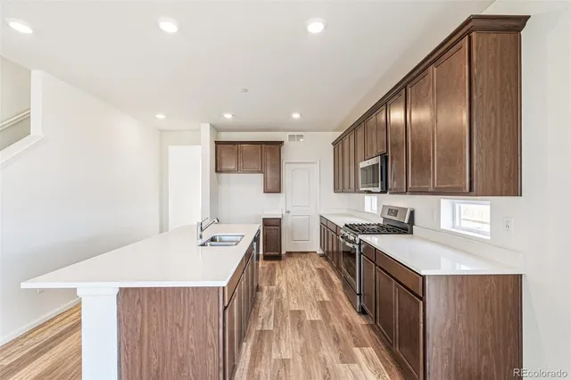 a kitchen with granite countertop a sink wooden floor and stainless steel appliances