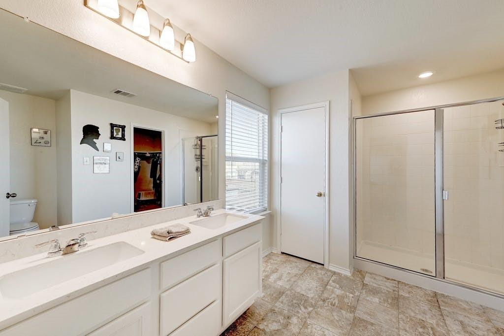 13916 Inaugural Street Manor, TX 78653 - Photo 19 of 28 Dual vanities and a spacious walk-in shower highlight this comfortable bathroom.