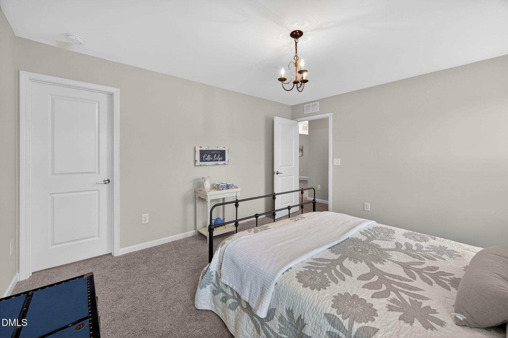 528 Spring Flower Court Cary, NC 27511 - Photo 37 of 51 a bedroom with a bed and a chandelier