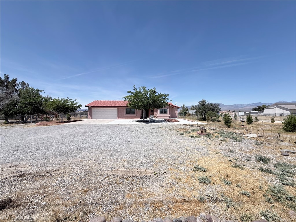 1220 East Gamebird Road Pahrump, NV 89048 - Photo 34 of 49 An inviting exterior with a wide gravel driveway leads to a single-story home set against a distant mountain backdrop.