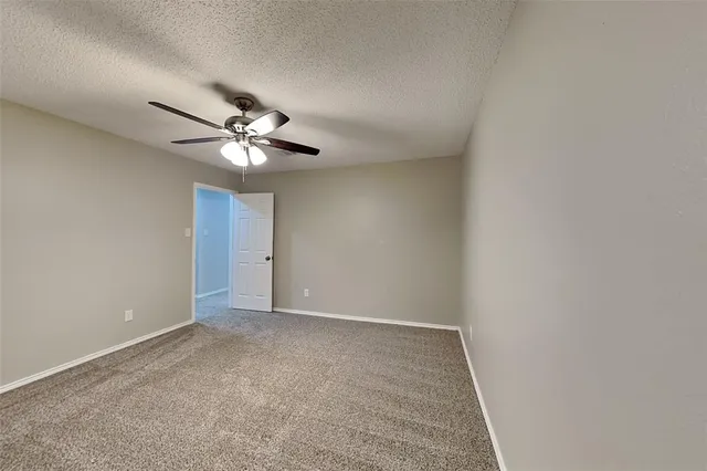 an empty room with a chandelier fan and windows