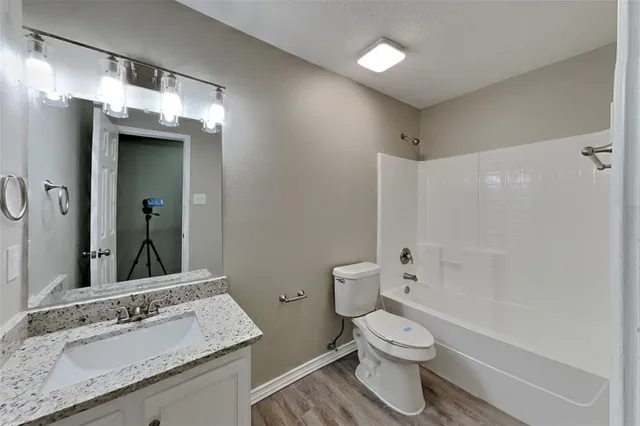 a bathroom with a granite countertop sink toilet a large mirror a shower and a bathtub