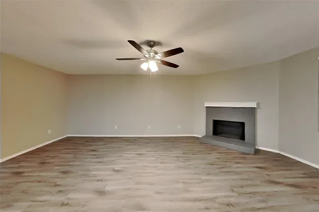 a view of an empty room with a fireplace and a ceiling fan