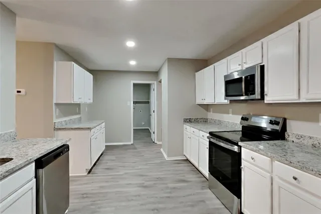 a kitchen with granite countertop cabinets stainless steel appliances and a counter space