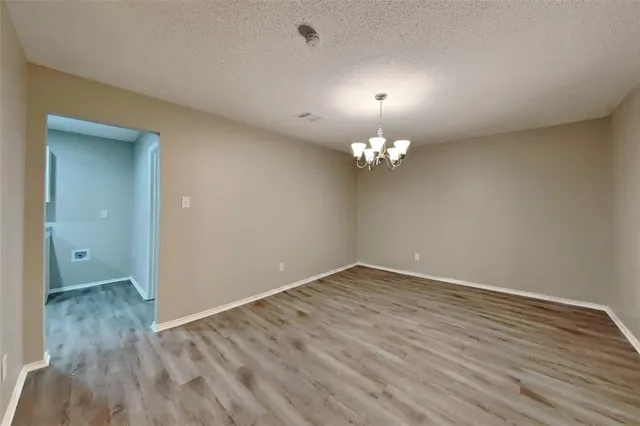 a view of an empty room with wooden floor and a chandelier