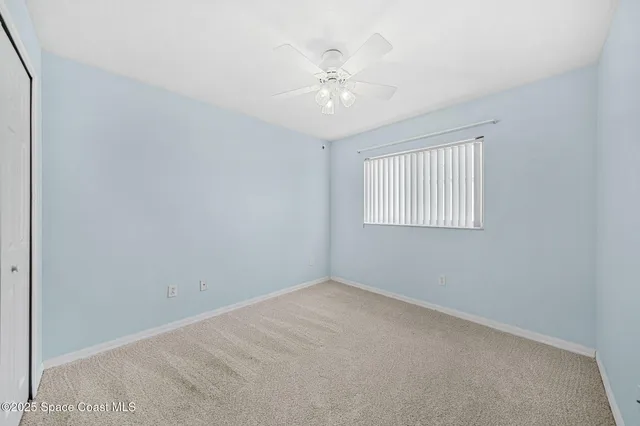 an empty room with windows and chandelier fan