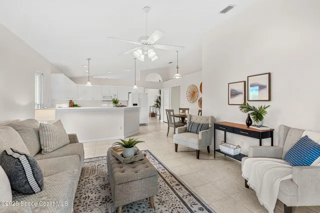 a living room with furniture kitchen view and a chandelier