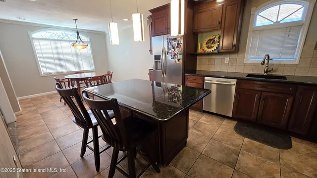 a kitchen with stainless steel appliances granite countertop a table chairs and a refrigerator