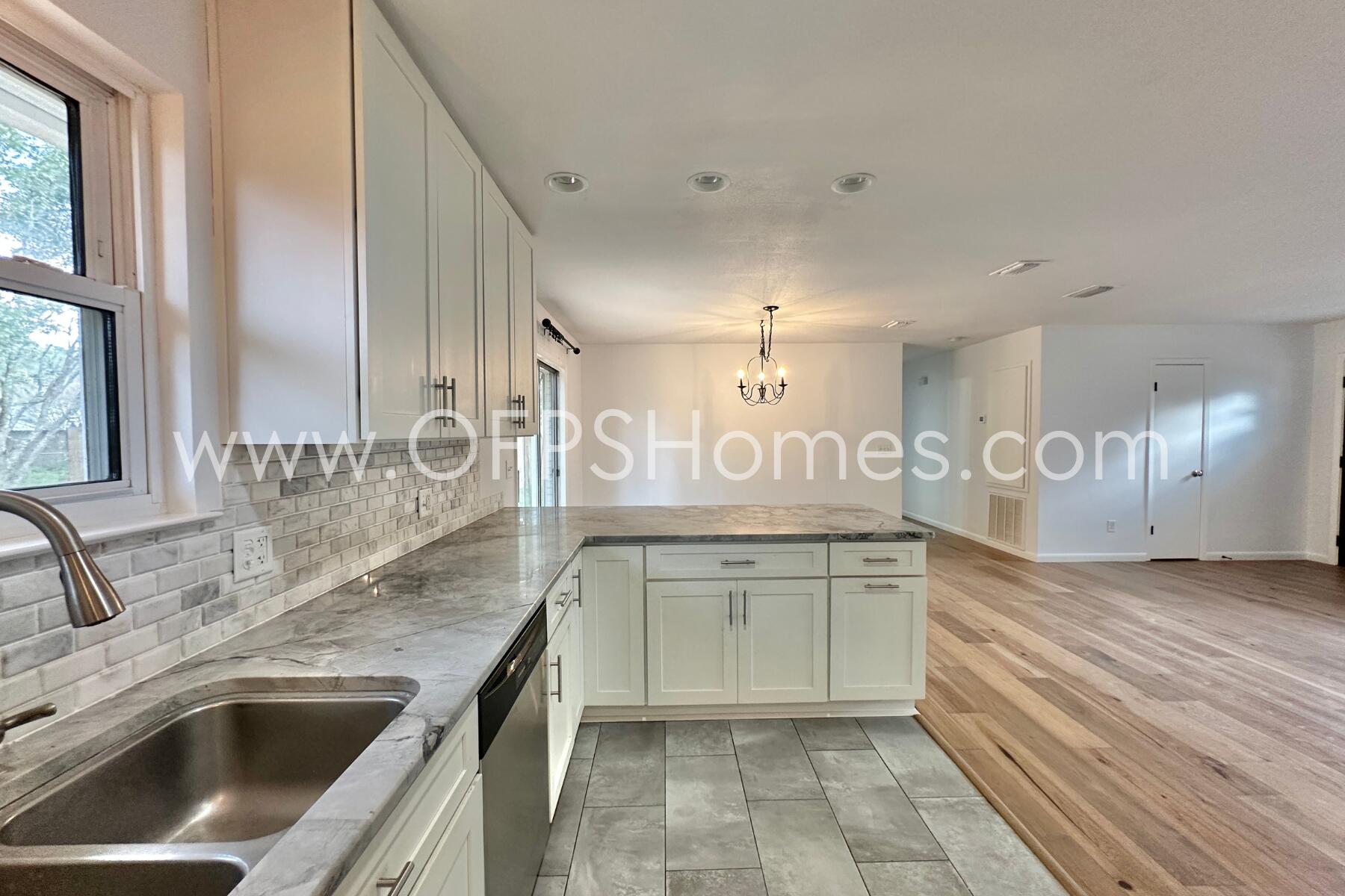 309 Pontevedra Lane Niceville, FL 32578 - Photo 11 of 32 a large kitchen with granite countertop a sink dishwasher a stove and a refrigerator with wooden floor