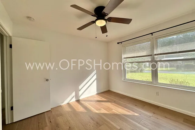 a view of an empty room with a window and wooden floor