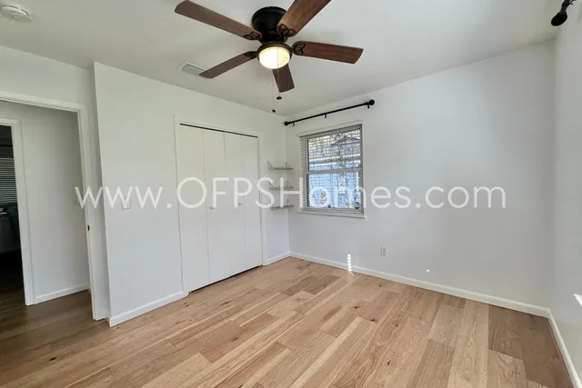 a view of empty room with wooden floor and fan