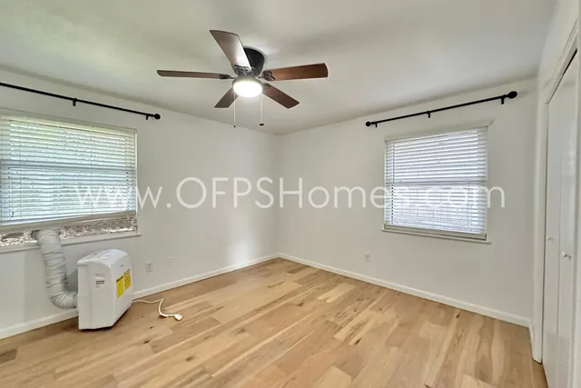 a view of a livingroom with a chandelier fan and wooden floor