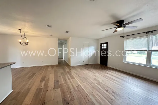 a view of a livingroom with wooden floor a ceiling fan and windows