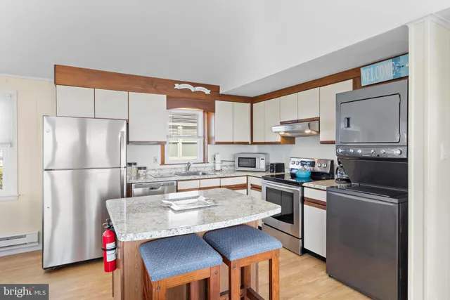 a kitchen with stainless steel appliances granite countertop a refrigerator a stove a sink dishwasher and white cabinets with wooden floor