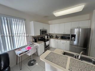 West Kendall Miami, FL 33193 - Photo 13 of 25 a kitchen with a refrigerator and white cabinets