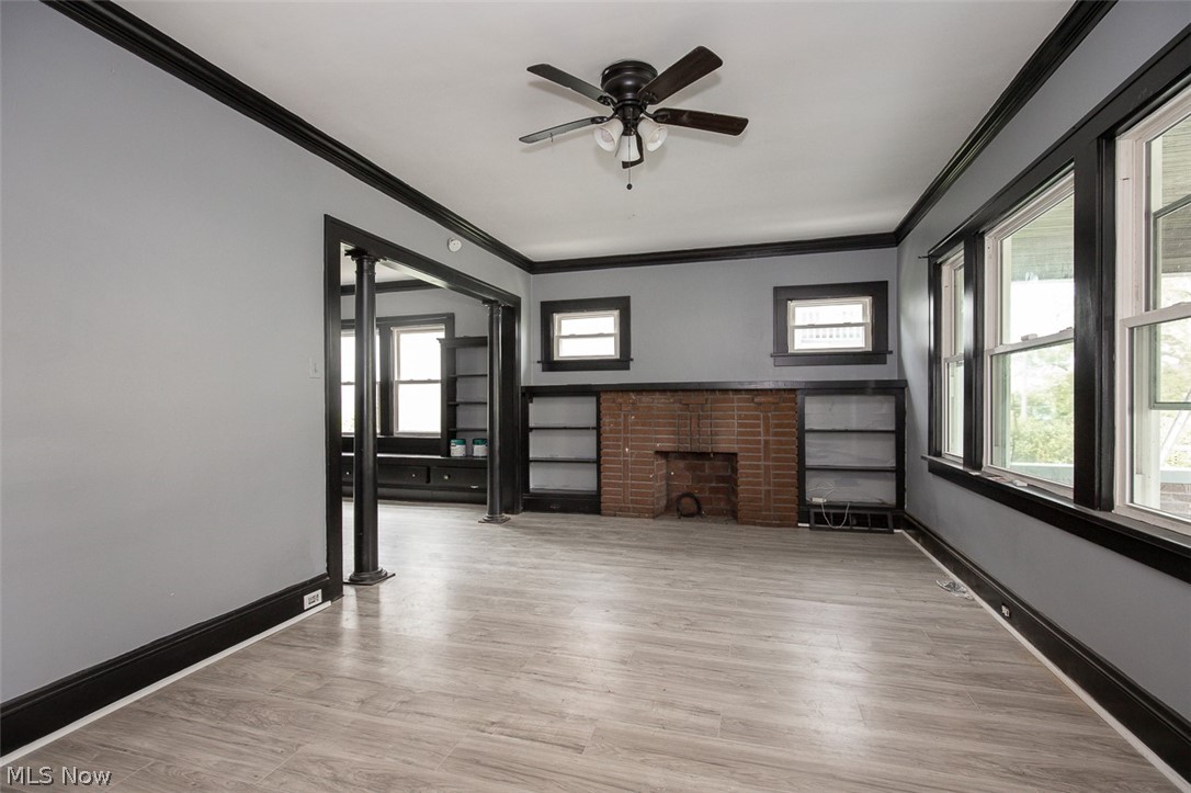 1868-1870 Lampson Road Cleveland, OH 44112 - Photo 20 of 36 Spacious room featuring wood-finish flooring, a brick fireplace with built-in shelving, multiple windows, and a ceiling fan
