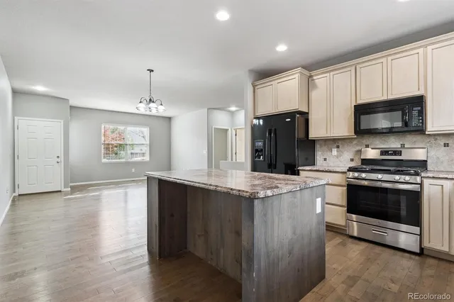 a kitchen with stainless steel appliances granite countertop a stove a sink and a refrigerator