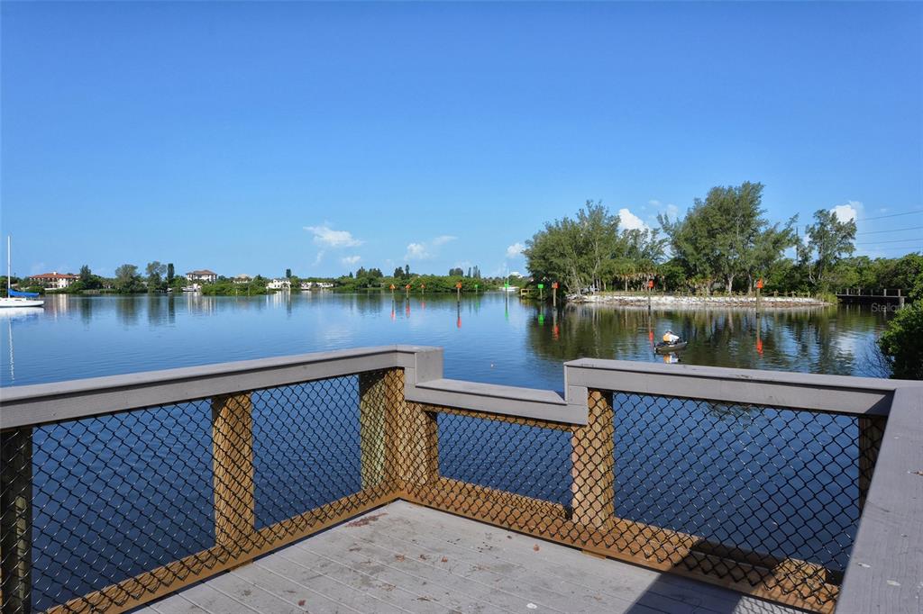 5100 Jessie Harbor Drive, Unit 504 Osprey, FL 34229 - Photo 61 of 87 a view of a lake with wooden stairs and bridge and trees in the background