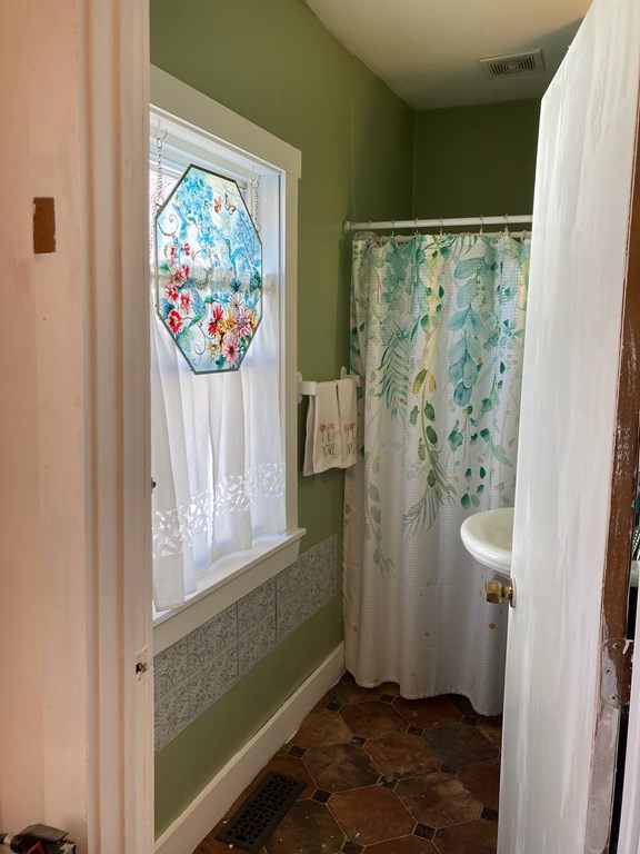45 Maple Street Warren, MA 01083 - Photo 14 of 20 a bathroom with a painting on the wall and a shower curtain