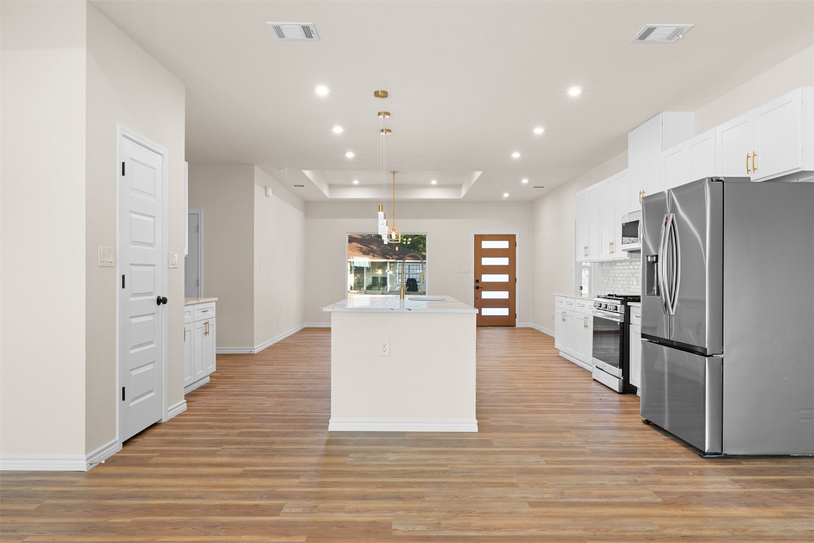 340 Cactus Street Giddings, TX 78942 - Photo 11 of 37 Kitchen with appliances with stainless steel finishes, pendant lighting, white cabinets, light wood-style flooring, and recessed lighting