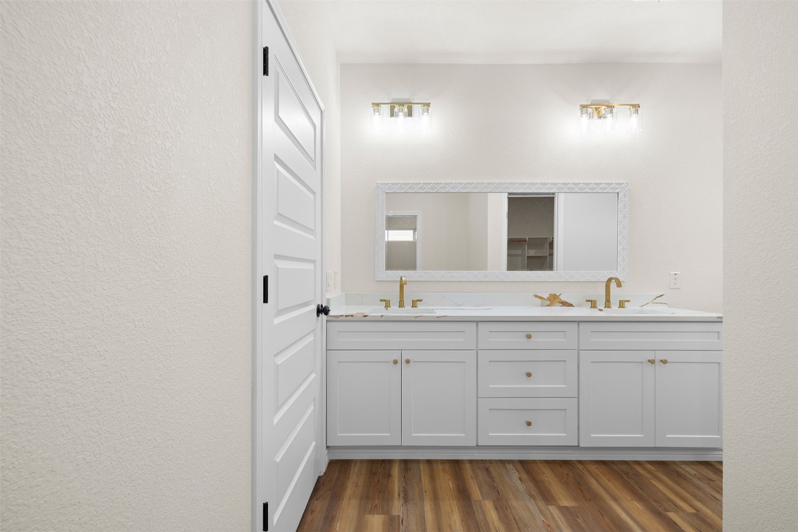 340 Cactus Street Giddings, TX 78942 - Photo 23 of 37 Full bathroom featuring a textured wall, double vanity, dark wood-style floors, and a closet