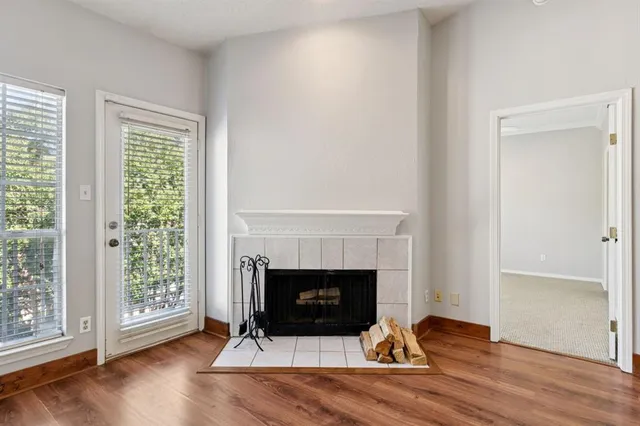 an empty room with wooden floor fireplace and windows
