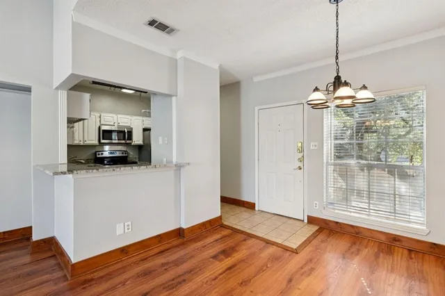 a view of a room with wooden floor kitchen view and a window