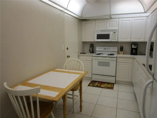 a kitchen with stainless steel appliances a stove a sink a microwave a dining table and chairs