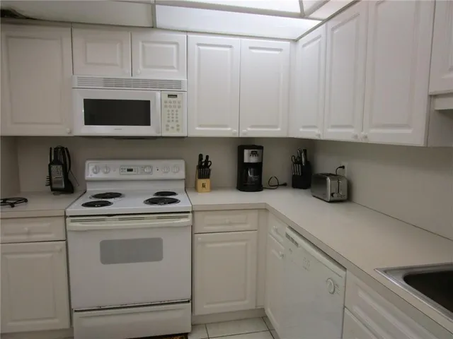 a kitchen with white cabinets and white appliances