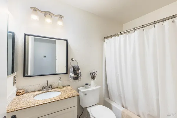 a bathroom with a granite countertop sink and a mirror with toilet