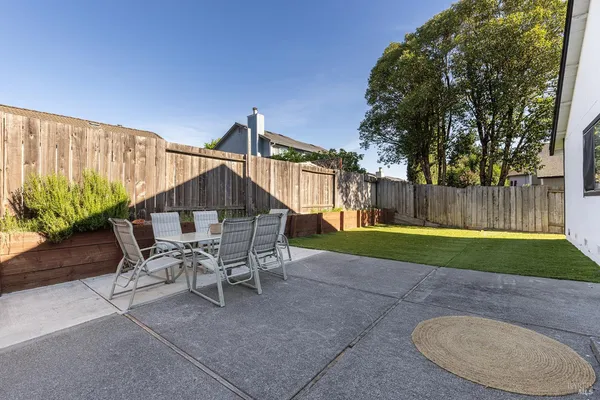 a patio with a table and chairs and potted plants