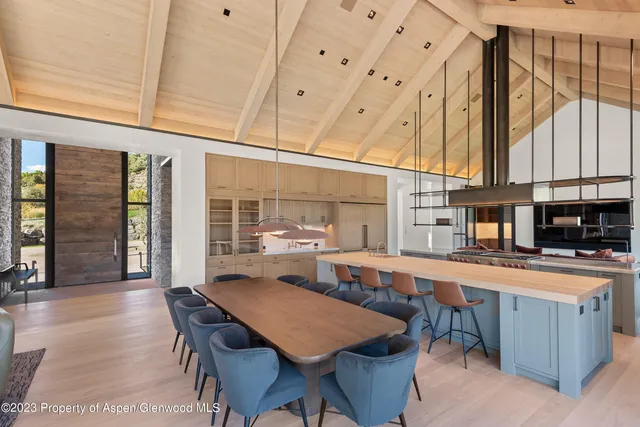 a room with stainless steel appliances kitchen island granite countertop a table chairs sink and cabinets