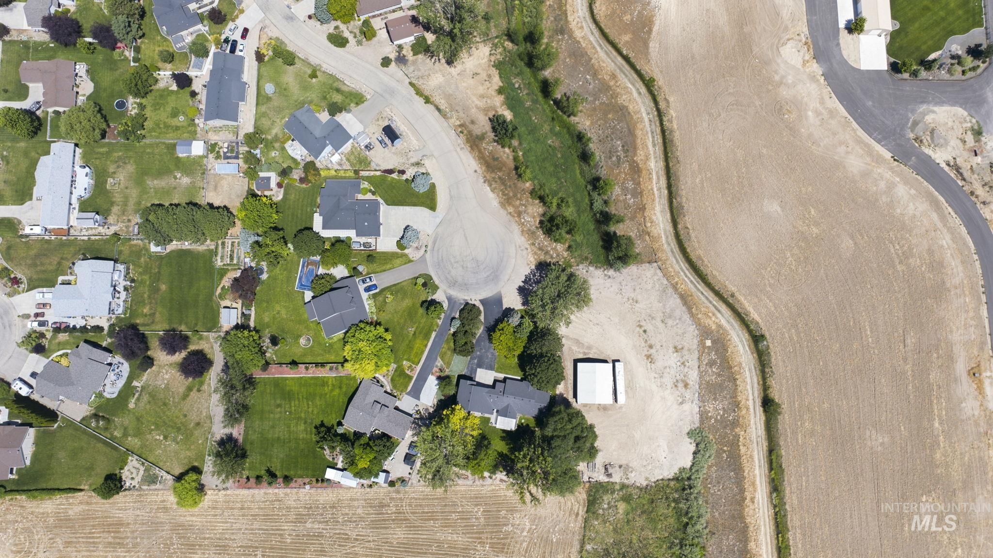 24864 Coventry Drive Caldwell, ID 83607 - Photo 43 of 49 Aerial view showcasing a residential development with individual properties, expansive green lawns, mature trees, a cul-de-sac, and agricultural land bordering the area