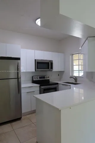 a kitchen with stainless steel appliances a refrigerator sink and microwave