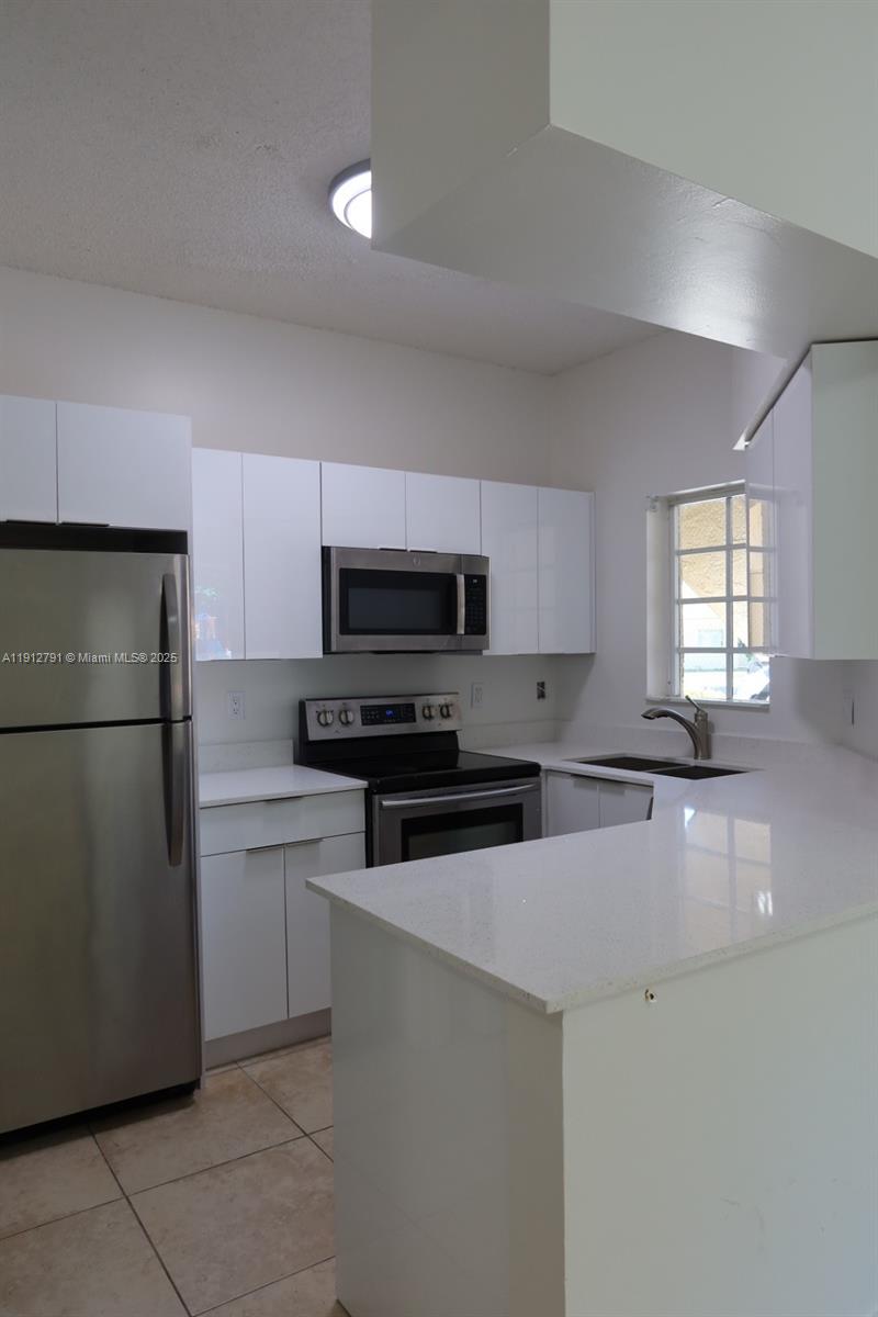 18340 Northwest 68th Avenue, Unit A Hialeah, FL 33015 - Photo 1 of 10 a kitchen with stainless steel appliances a refrigerator sink and microwave