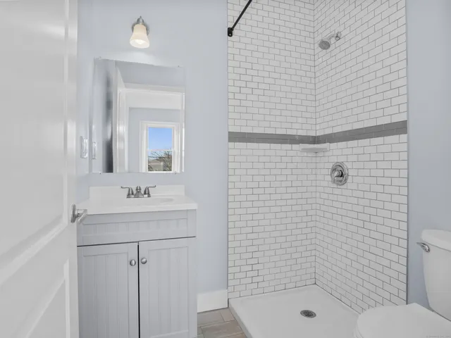 a bathroom with a shower a sink a toilet and mirror