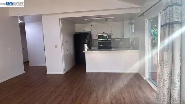 a view of kitchen with stainless steel appliances wooden floor and chair