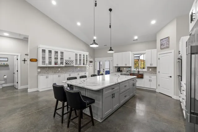 a kitchen with stainless steel appliances kitchen island granite countertop a table chairs and a refrigerator