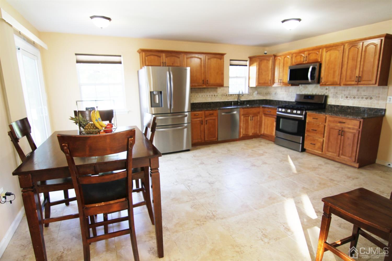 14 Pointer Place Kendall Park, NJ 08824 - Photo 17 of 34 a kitchen with granite countertop stainless steel appliances a refrigerator a stove a dining table and chairs