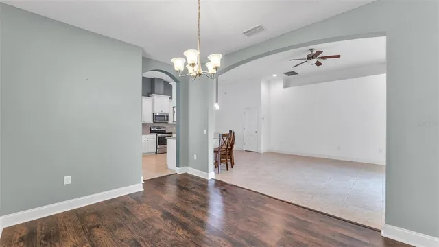 a view of a livingroom with a chandelier fan and wooden floor
