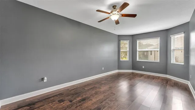 a view of an empty room with a window and wooden floor