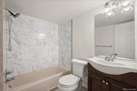 a bathroom with a sink a toilet a mirror a bathtub and shower