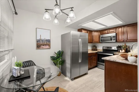 a kitchen with stainless steel appliances granite countertop a refrigerator a stove a sink dishwasher a dining table and chairs with wooden floor
